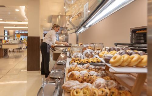 una mujer parada detrás de un mostrador en una panadería en Hotel RH Corona del Mar 4* Sup, en Benidorm