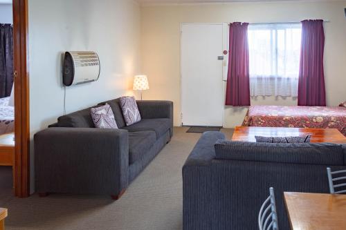 a living room with a couch and a bed at New Haven Motel in Auckland