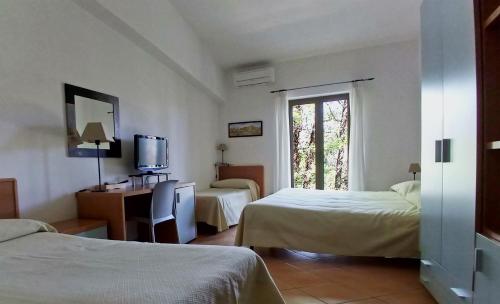 una camera d'albergo con due letti e una televisione di Verdeblu Country Hotel a San Giovanni a Piro