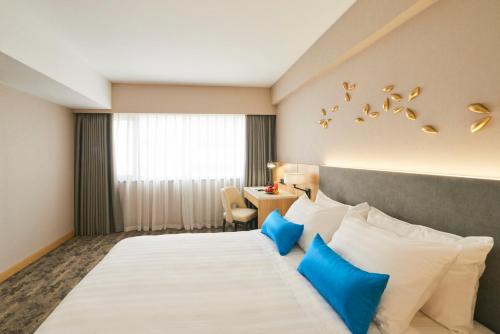 a hotel room with a bed with blue and white pillows at Hanoi Hotel in Hanoi