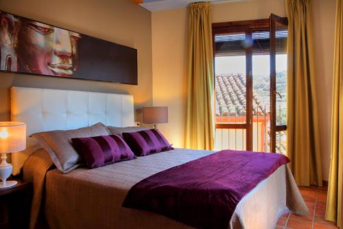 a bedroom with a bed with purple pillows and a window at Apartamentos Casa Molinero in Buera