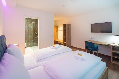 a hotel room with two beds and a desk and a television at Thermalhotel Aulendorf in Aulendorf