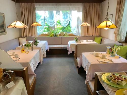 ein Esszimmer mit vier Tischen und einem Fenster in der Unterkunft Hotel Burgleitenhof in Lana