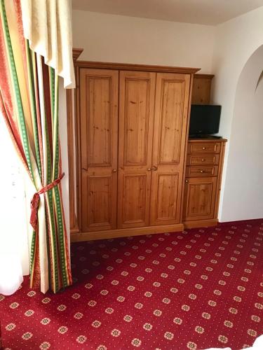 a bedroom with wooden cabinets and a red carpet at Garni Hotel Burgleitenhof in Lana