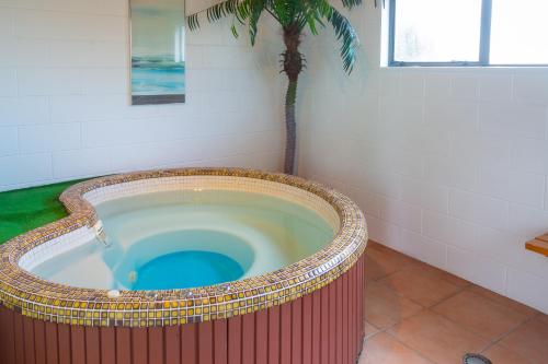 a jacuzzi tub with a palm tree in a bathroom at New Haven Motel in Auckland