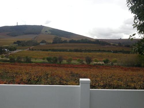 a white fence in front of a field with a hill at D'Aria Guest Cottages in Durbanville
