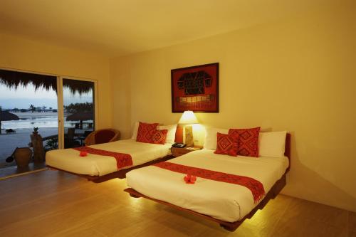 a hotel room with two beds and a window at Bluewater Maribago Beach Resort in Mactan