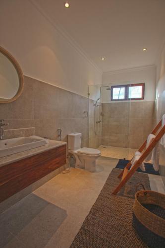 a bathroom with a tub and a toilet and a sink at Asali Beach House in Jambiani