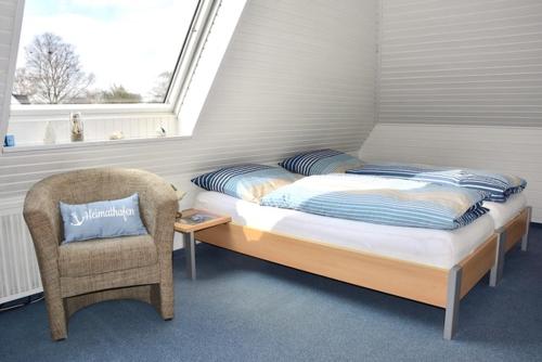 a bedroom with a bed and a chair and a window at Gaestehaus Kiekmolrin in Gnarrenburg