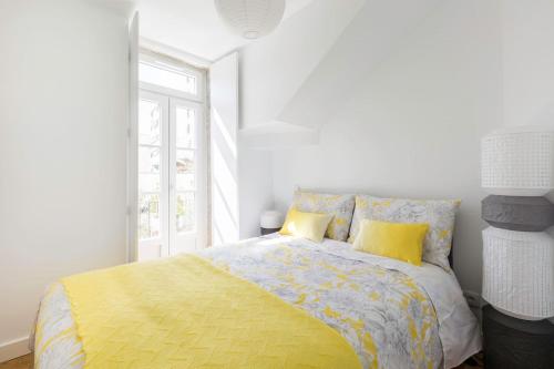 a bedroom with a bed with yellow sheets and a window at Charming duplex with portuguese soul in Lisbon
