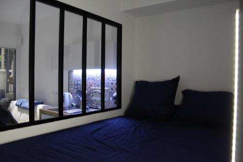 - une chambre avec une grande fenêtre et un lit bleu dans l'établissement Alex Nice Studio, à Nice