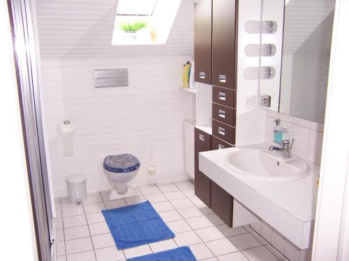 La salle de bains blanche est pourvue d'un lavabo et de toilettes. dans l'établissement Gaestehaus Kiekmolrin, à Gnarrenburg