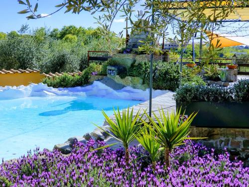 un giardino con fiori viola e una piscina di Piccolo Feudo Green Resort a Viterbo