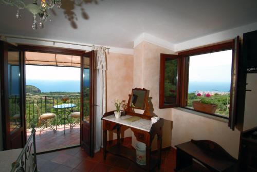 a room with a balcony with a table and windows at Hotel Relais Pian delle Starze in Marina di Camerota