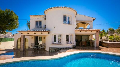 une villa avec piscine devant une maison dans l'établissement Casa Los Pinos, à Benissa