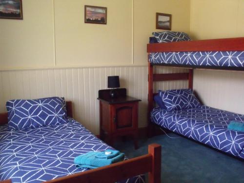 
a bed room with two bunk beds and a desk at Blue Wren Riverside Cottage in Westerway
