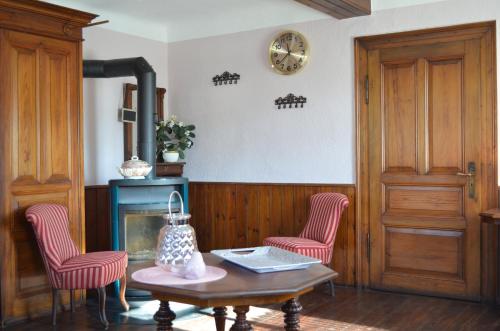 a living room with a table and two chairs and a clock at Villa Merzbach - Wohnen wie im Museum mit Komfort in Untermerzbach