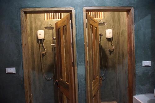 a bathroom with two wooden doors and a shower at Hiraya Surf Hostel in General Luna