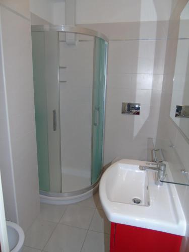 a white bathroom with a shower and a sink at Residenza Sporting in Lignano Sabbiadoro