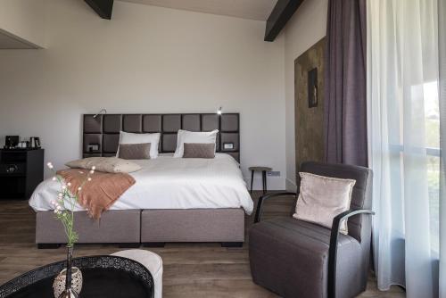 a bedroom with a large bed and a chair at Fruitpark Hotel & Spa in Ochten
