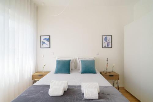 een slaapkamer met een groot bed met 2 blauwe kussens bij LAZ apartment in Porto