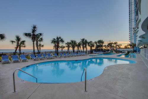 a large swimming pool with chairs and the beach at Oceanfront Paradise in the Heart of Myrtle Beach in Myrtle Beach
