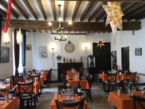 un restaurant avec des tables et des chaises orange et une horloge dans l'établissement Les Gentianes, à Allos
