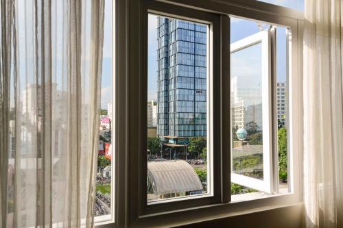 a window with a view of a tall building at Saigonciti Hotel A in Ho Chi Minh City