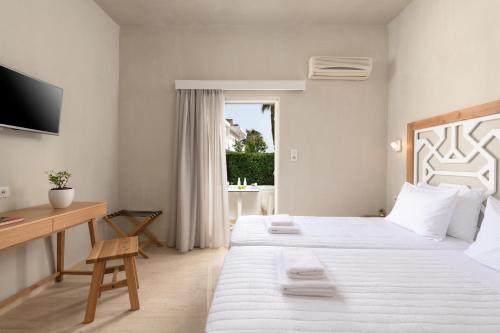 a bedroom with two beds and a desk and a television at Apollo Plakias in Plakias