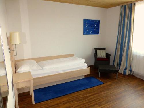 a small bedroom with a bed and a chair at Hotel Krone Langenegg in Langenegg