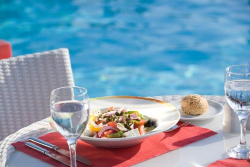 a table with a plate of food and glasses of water at Novotel Athens in Athens