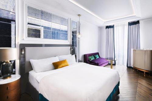 ein Hotelzimmer mit einem weißen Bett und einem lila Stuhl in der Unterkunft Sofia Balkan Palace in Sofia