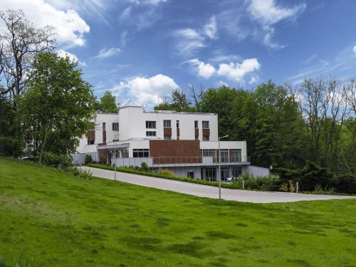 a white building on a hill with a green field at Wielspin Puszczykowo in Puszczykowo