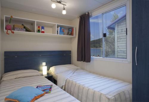 two beds in a room with a window at Camping Village Lago Maggiore in Dormelletto