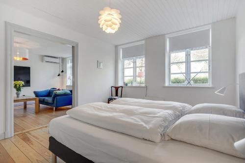 Habitación blanca con 2 camas y lámpara de araña. en Hotel apartment with a lake view - 2 room apartment, en Kruså