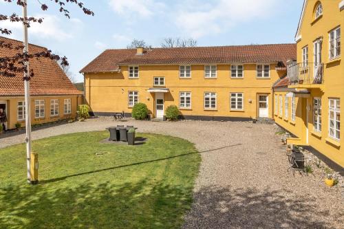a large yellow building with a yard in front of it at Hotel apartment with a lake view - 2 room apartment in Kruså