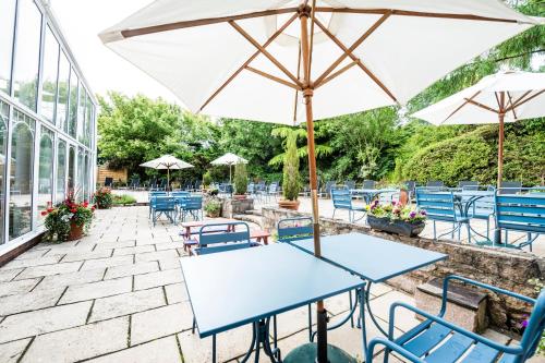 a patio area with tables, chairs and umbrellas at Parkway Hotel & Spa in Newport