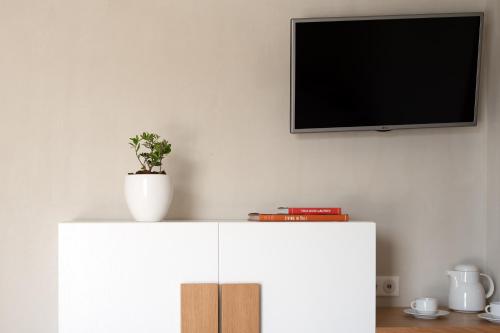a tv on top of a white cabinet with a plant on it at Apollo Plakias in Plakias