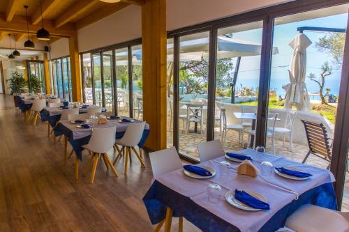 a dining room with tables and chairs and windows at Alban Eco Hotel in Dhërmi