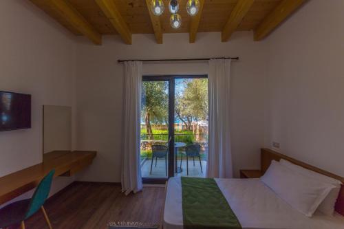 a bedroom with a bed and a sliding glass door at Hildon Eco Hotel in Dhërmi