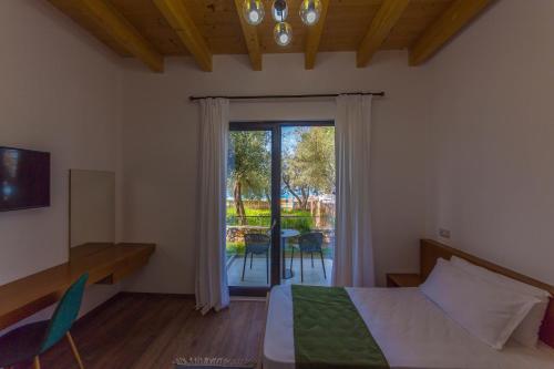 a bedroom with a bed and a sliding glass door at Alban Eco Hotel in Dhërmi