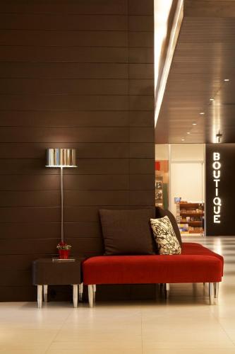 a red bench in a lobby with a lamp at Novotel Athens in Athens