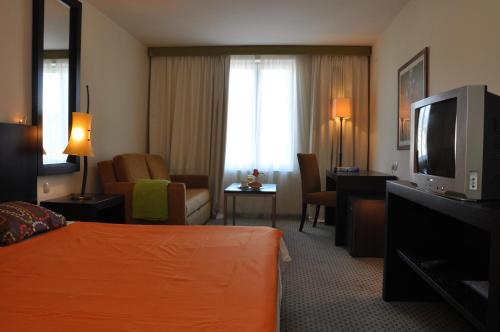um quarto de hotel com uma cama e uma televisão de ecrã plano em Hotel International em Rab