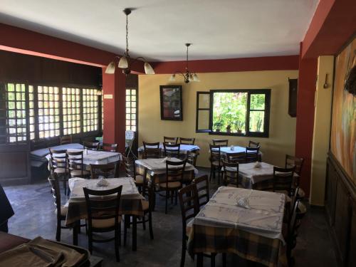 a dining room with tables and chairs and windows at Pension Skala in Ágios Matthaíos