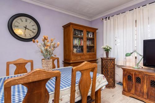 a dining room with a table and a clock on the wall at Lisbon South Bay Rooms in Amora