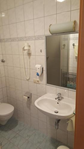 a bathroom with a sink and a toilet and a mirror at Restaurant Gästehaus Seiger in Sankt Lorenzen bei Knittelfeld