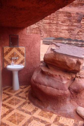 a bathroom with a sink next to a rock at Jordan Tracks Bedouin Camp in Wadi Rum