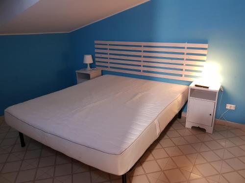 ジャルディーニ・ナクソスにあるAppartamento Dromのベッドルーム1室(青い壁の大きな白いベッド1台付)