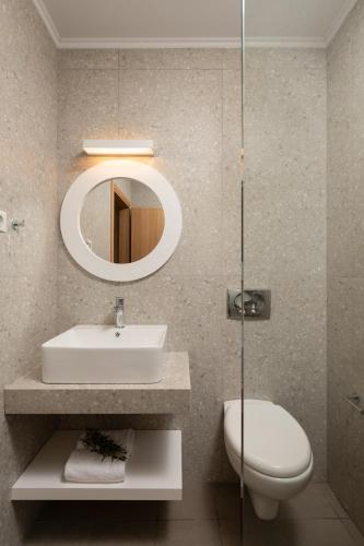 a bathroom with a sink and a toilet and a mirror at Apollo Plakias in Plakias