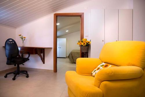 a living room with a yellow chair and a desk at A Casa dos Girassóis in Cuba